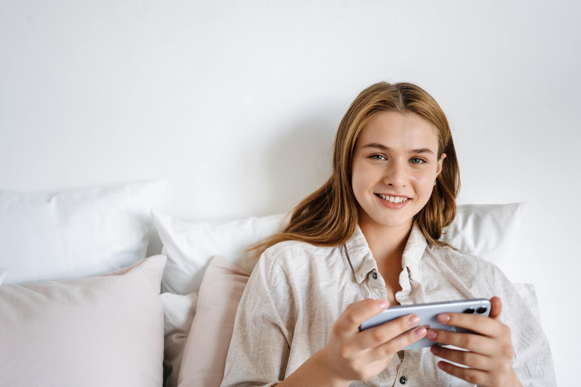 Beautiful smiling nice girl playing video game on cellphone