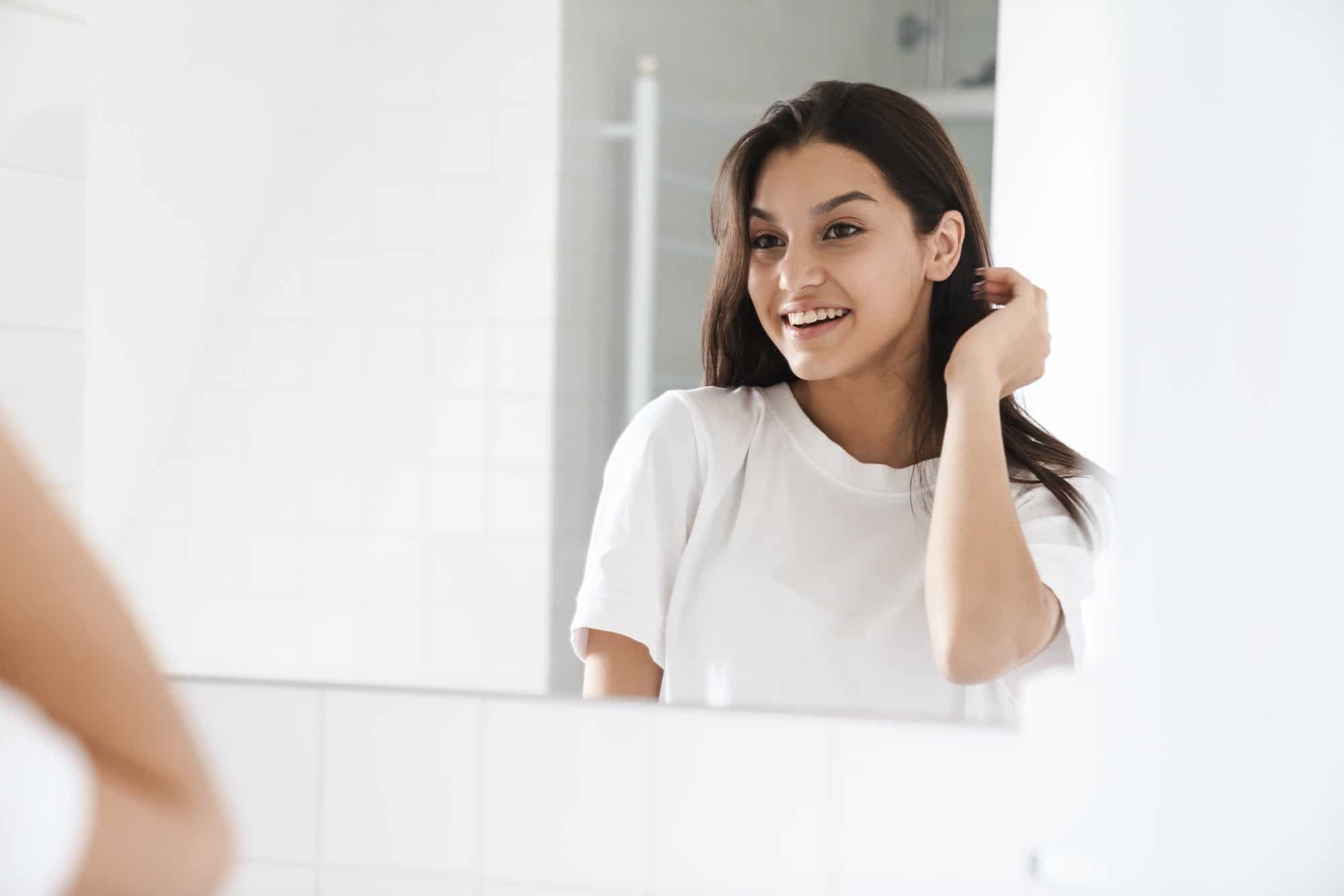 Photo of cheerful nice woman smiling while looking at mirror