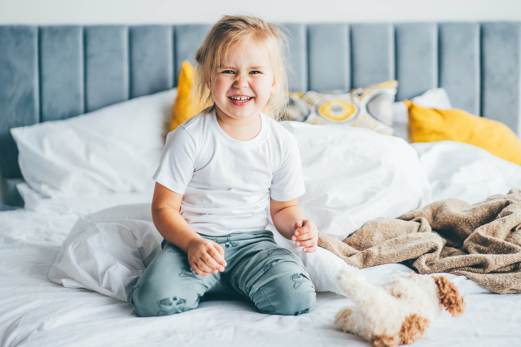 Portrait of laughing baby girl on bed.