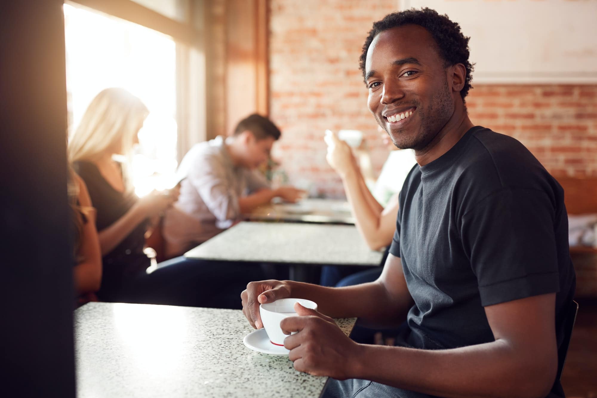 Portrait Of Smiling Man Sitting At Table In Coffee Shop